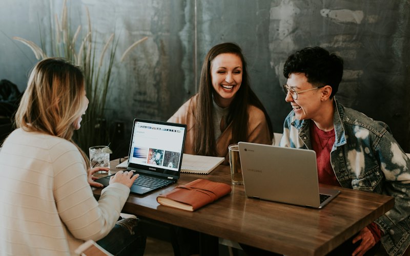 Estudantes reunidos em volta de uma mesa com notebooks.