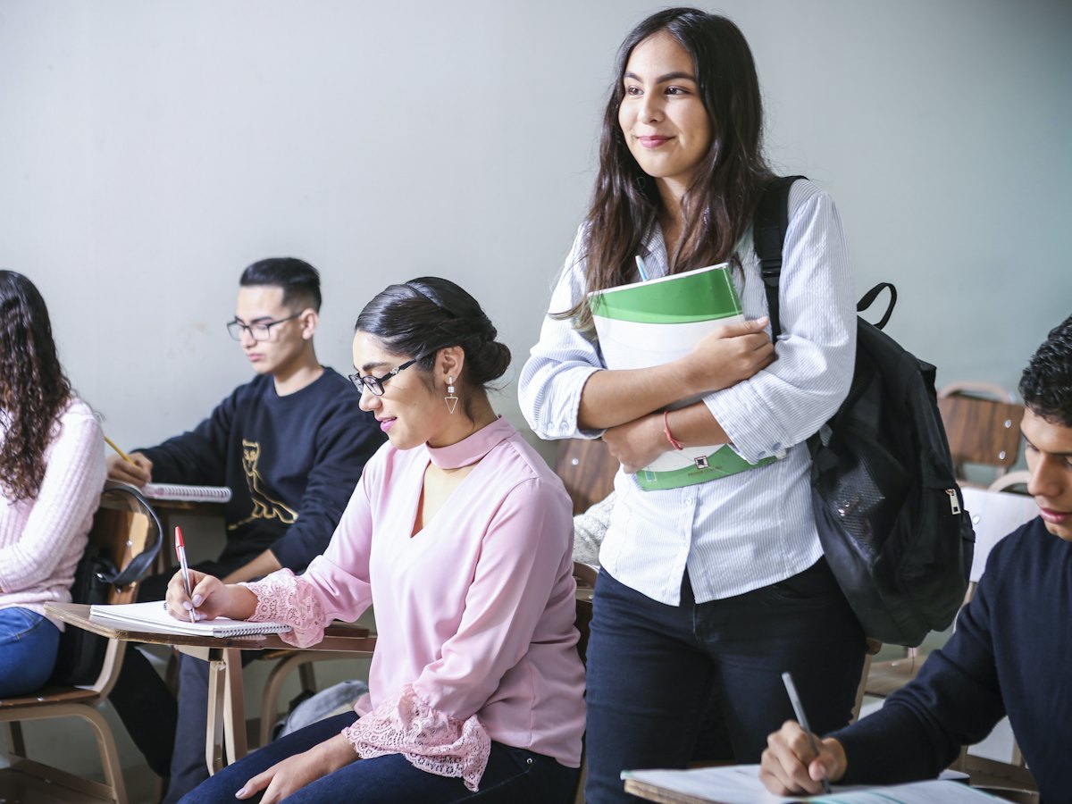 Professora em sala de aula com alunos sentados nas carteiras.